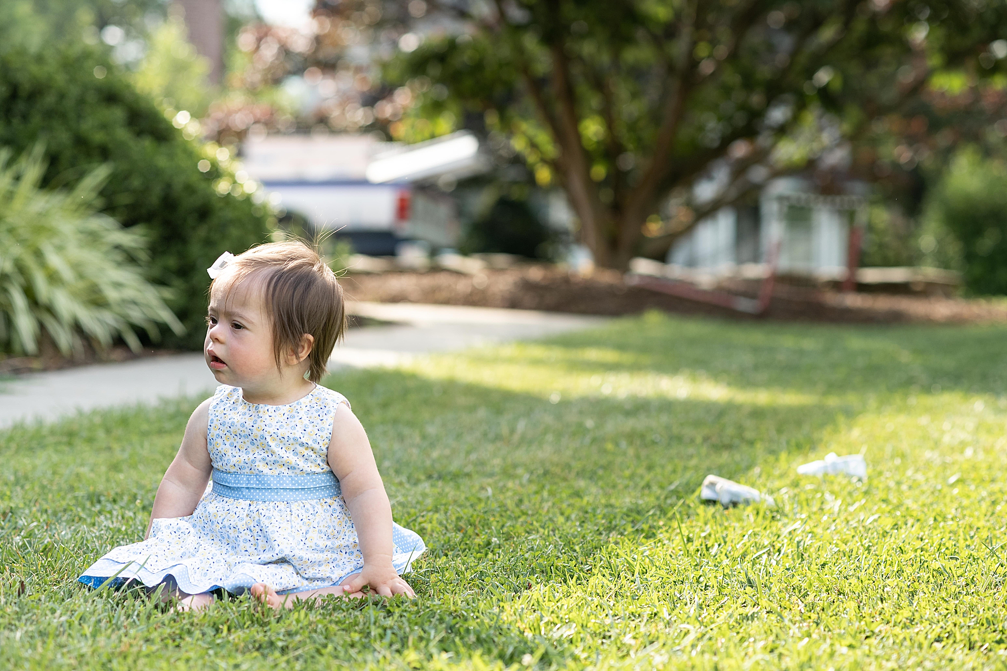 baby girl with Down syndrome sits on lawn during first birthday portraits