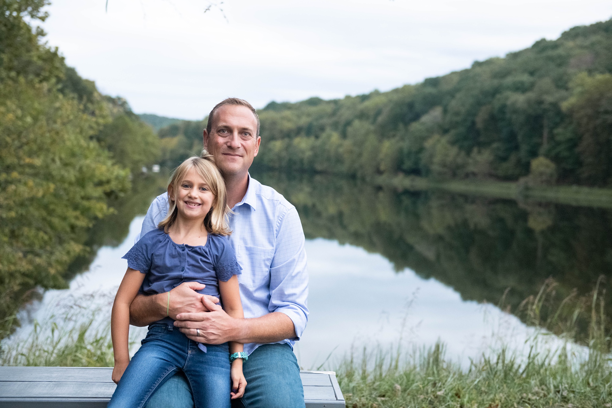 dad and daughter sit on bench during Photo Session in Lake Linganore