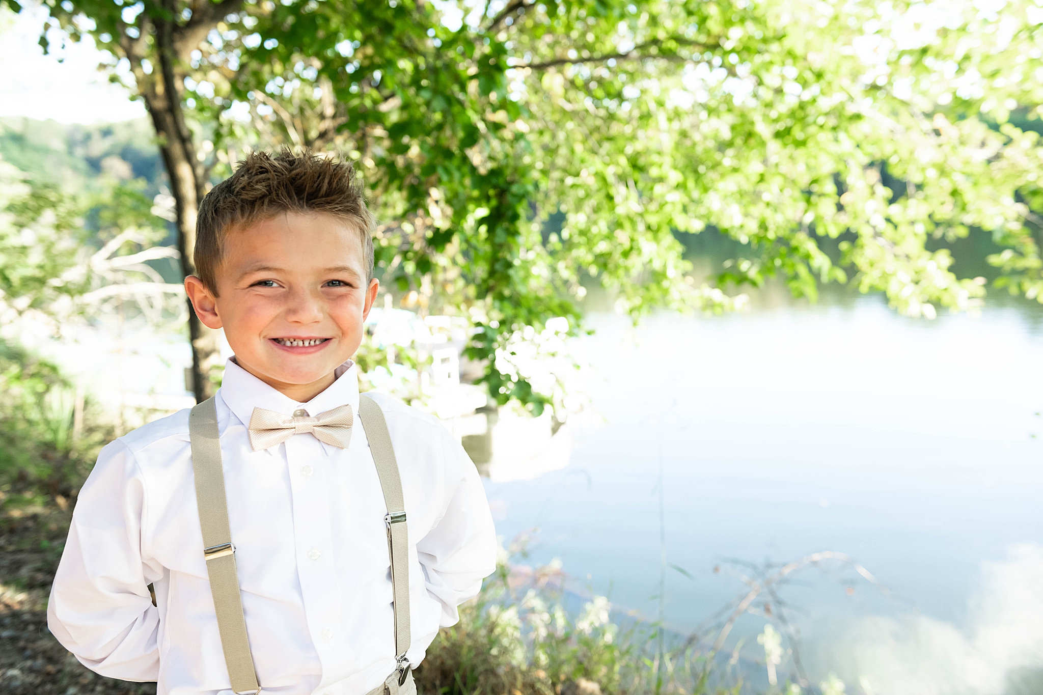 toddler in suspenders poses by Lake Linganore