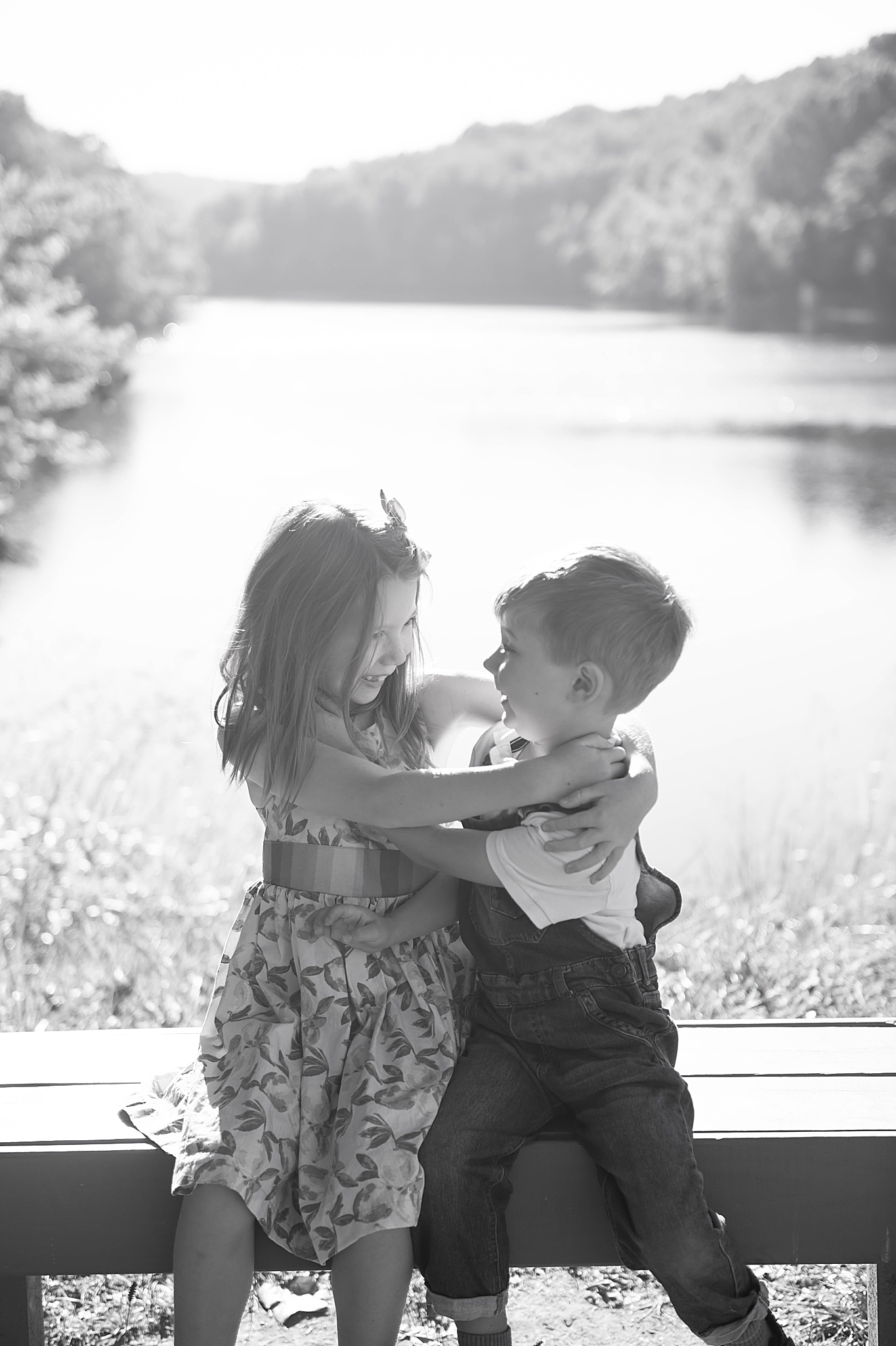 siblings hug on bench along Lake Linganore