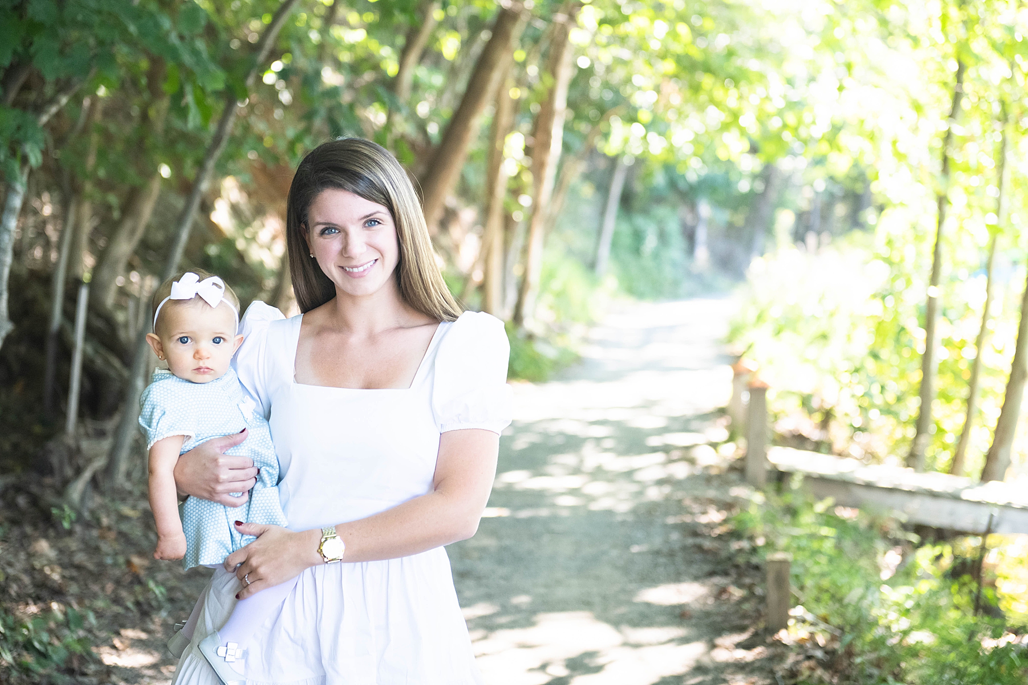mom holds baby girl during lakefront family photo session