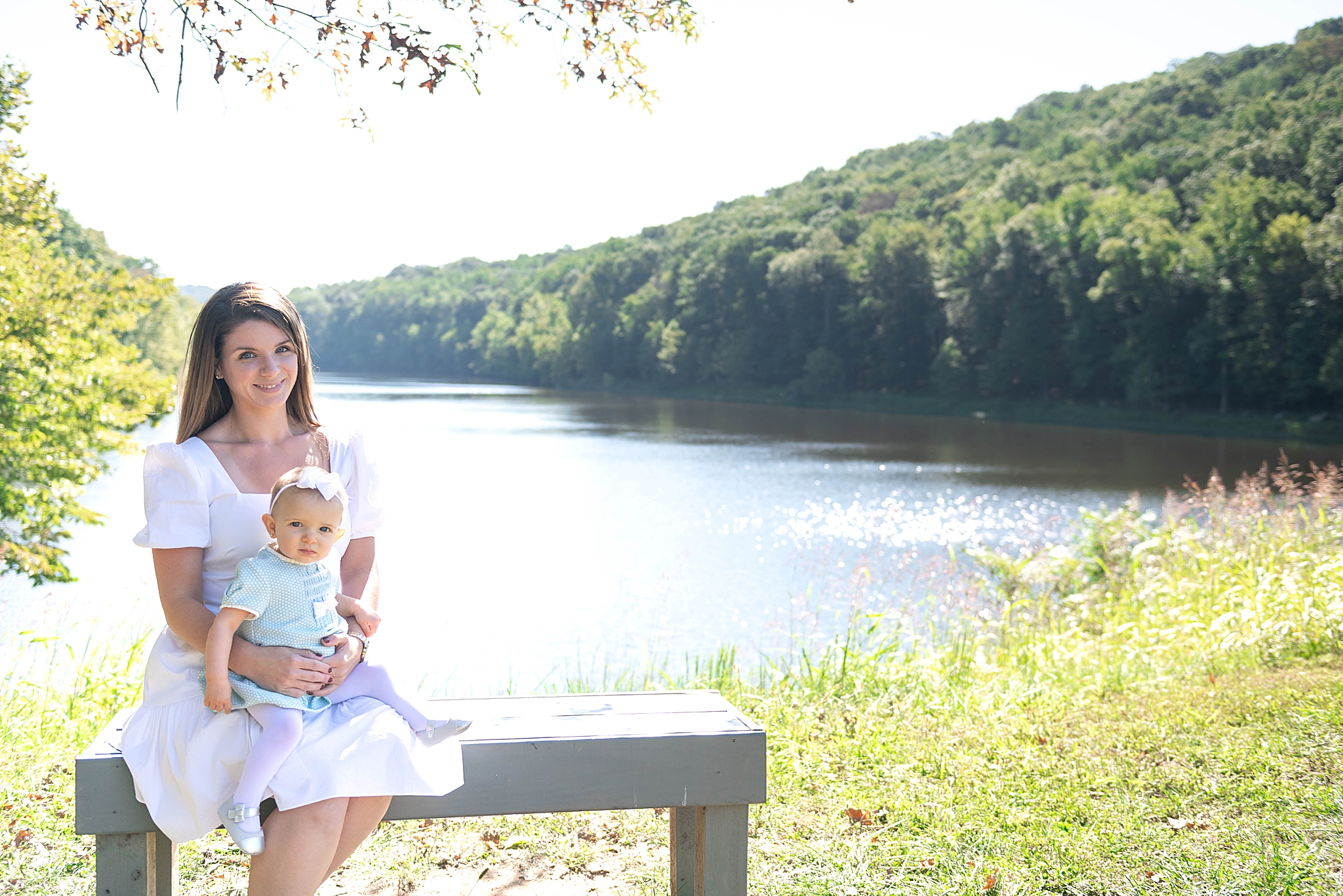 mom holds baby girl on bench in Lake Linganore
