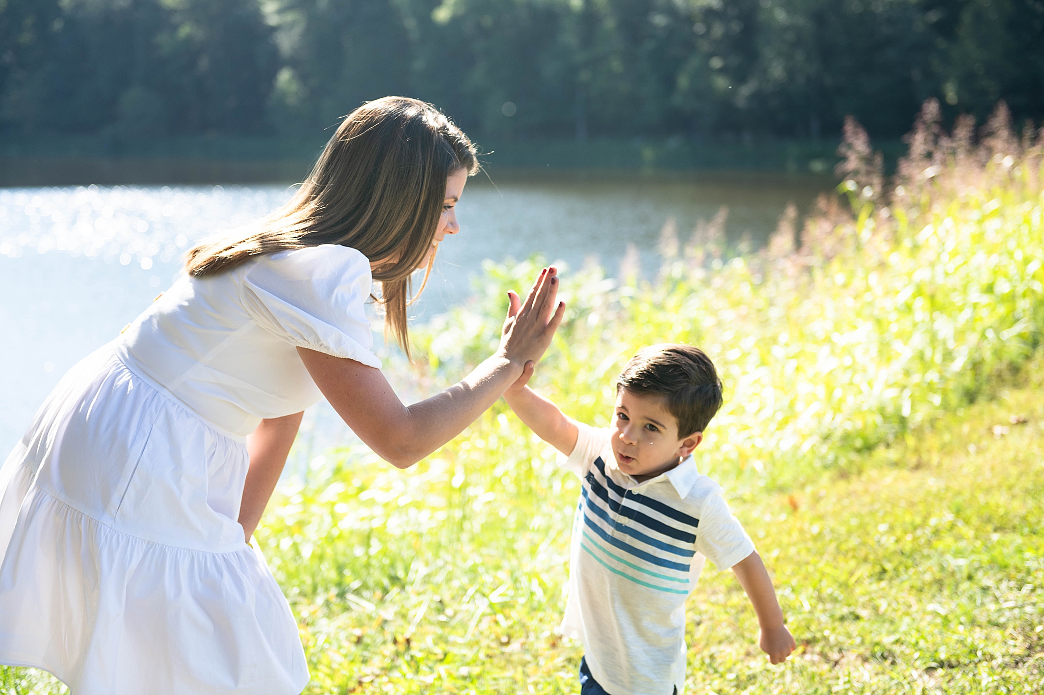 mom high fives toddler during lakefront family photo session in Maryland