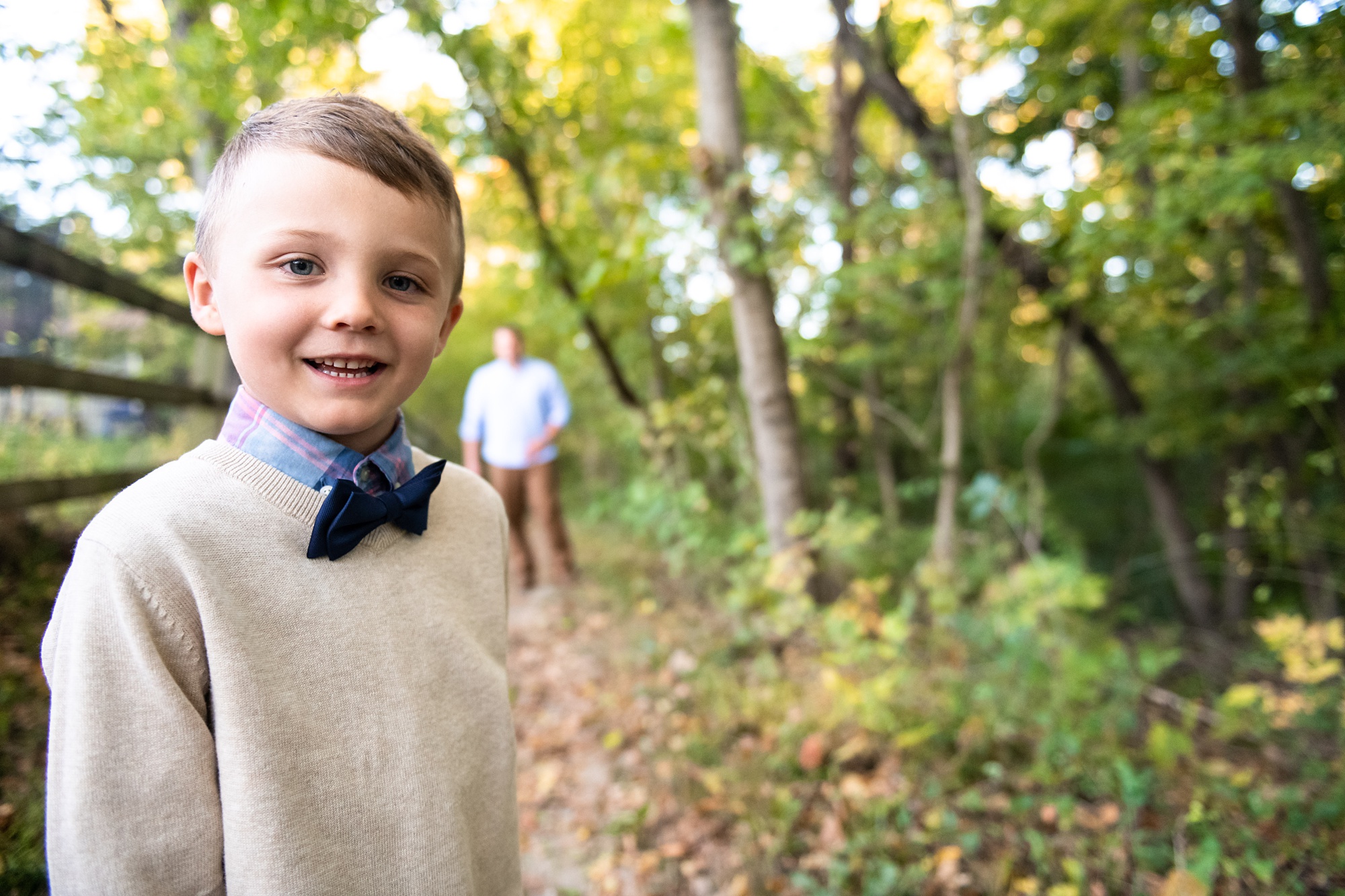 toddler poses with bowtie along fence line