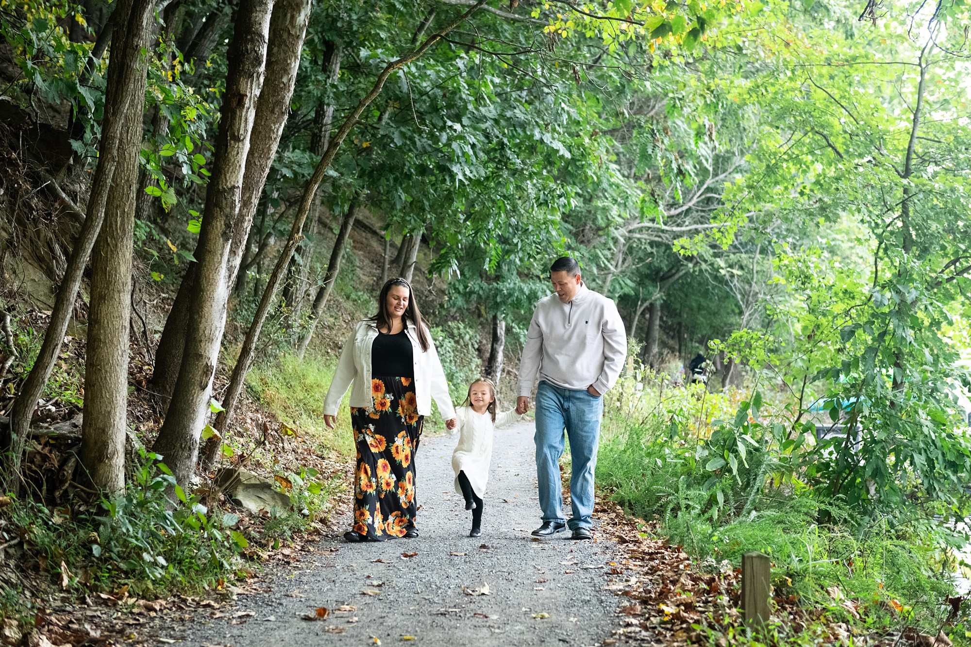 family of three walks on pathway along Lake Linganore