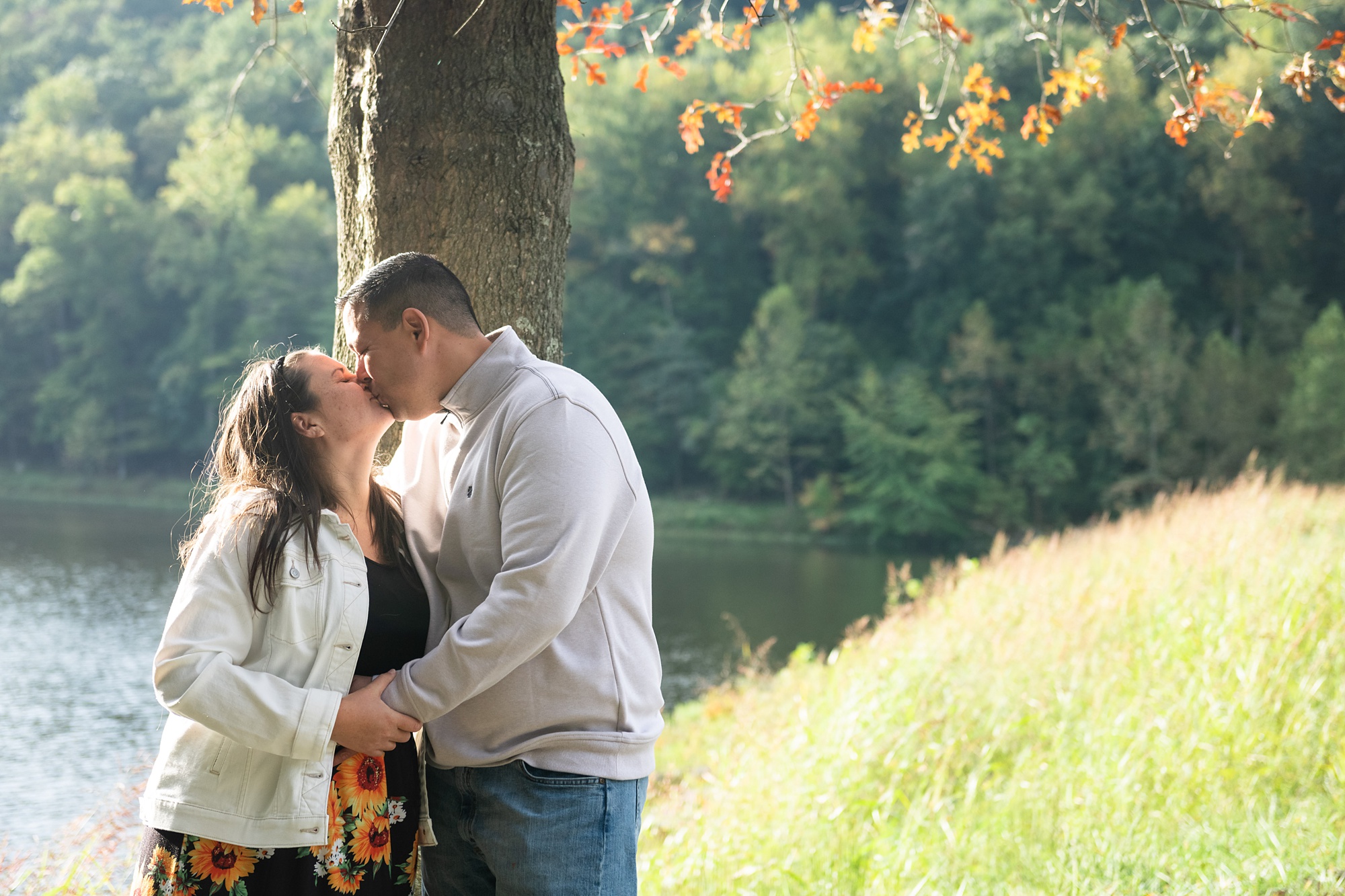 husband and wife kiss during maternity session at Lake Linganore