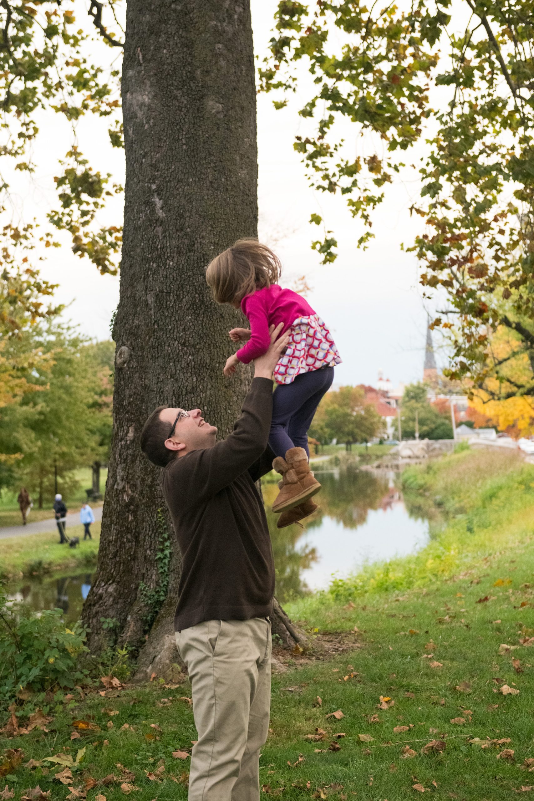dad lifts daughter in the air during fall family photos 