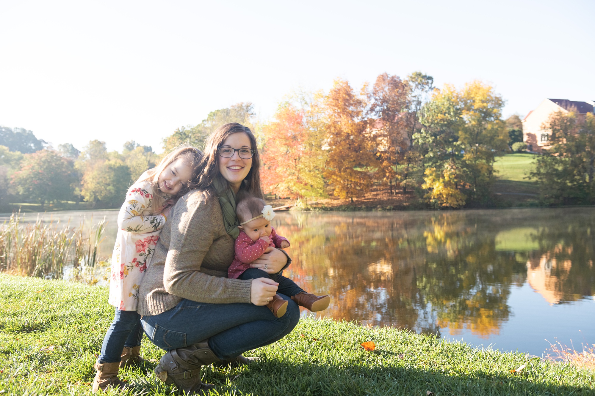mom poses with daughters by lake in Frederick County 