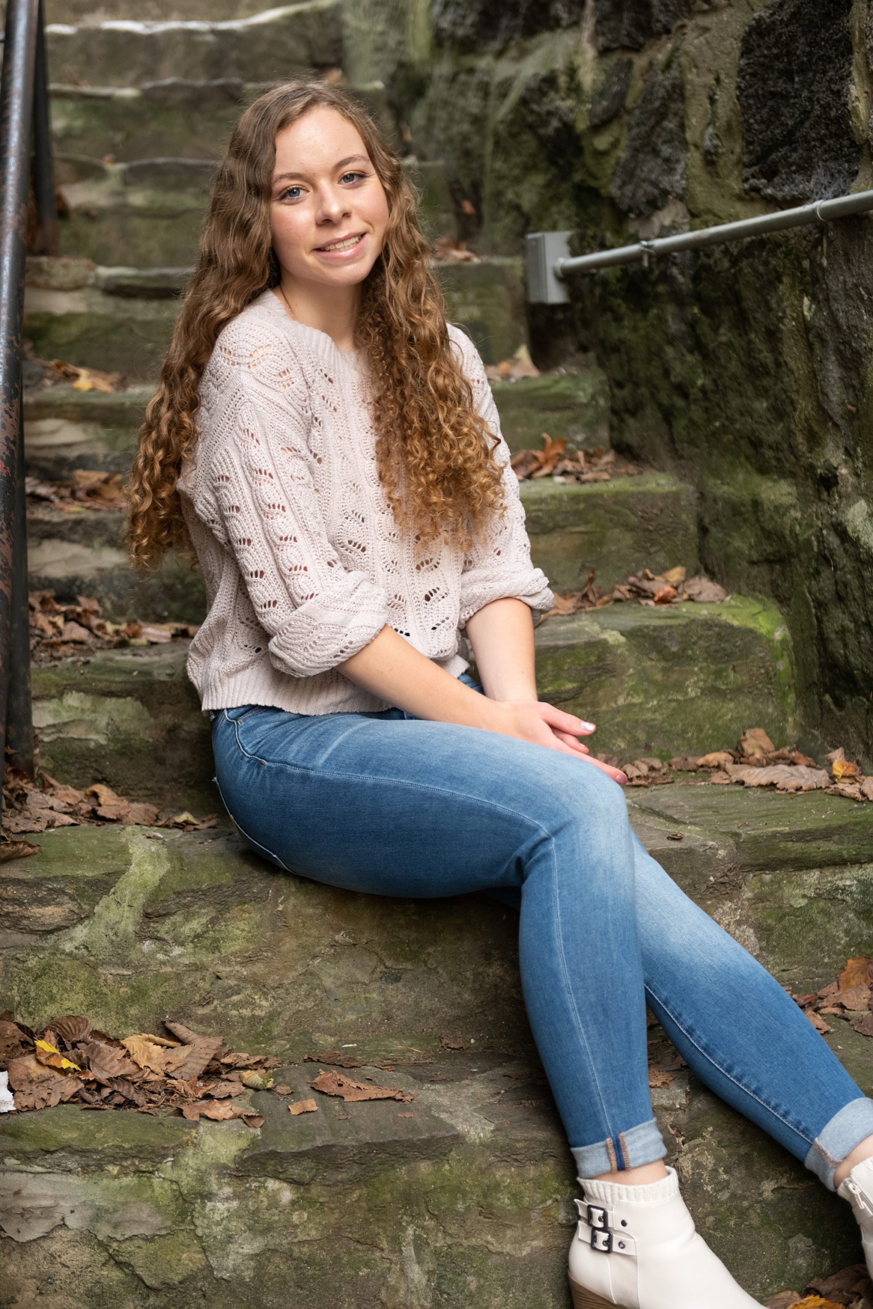 senior sits on moss covered steps in downtown Ellicott City