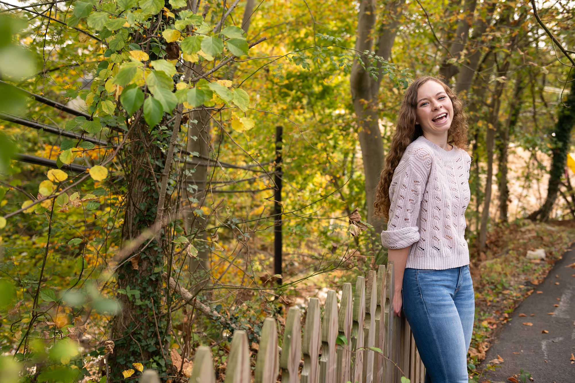 senior girl laughs against wooden fence in Ellicott City