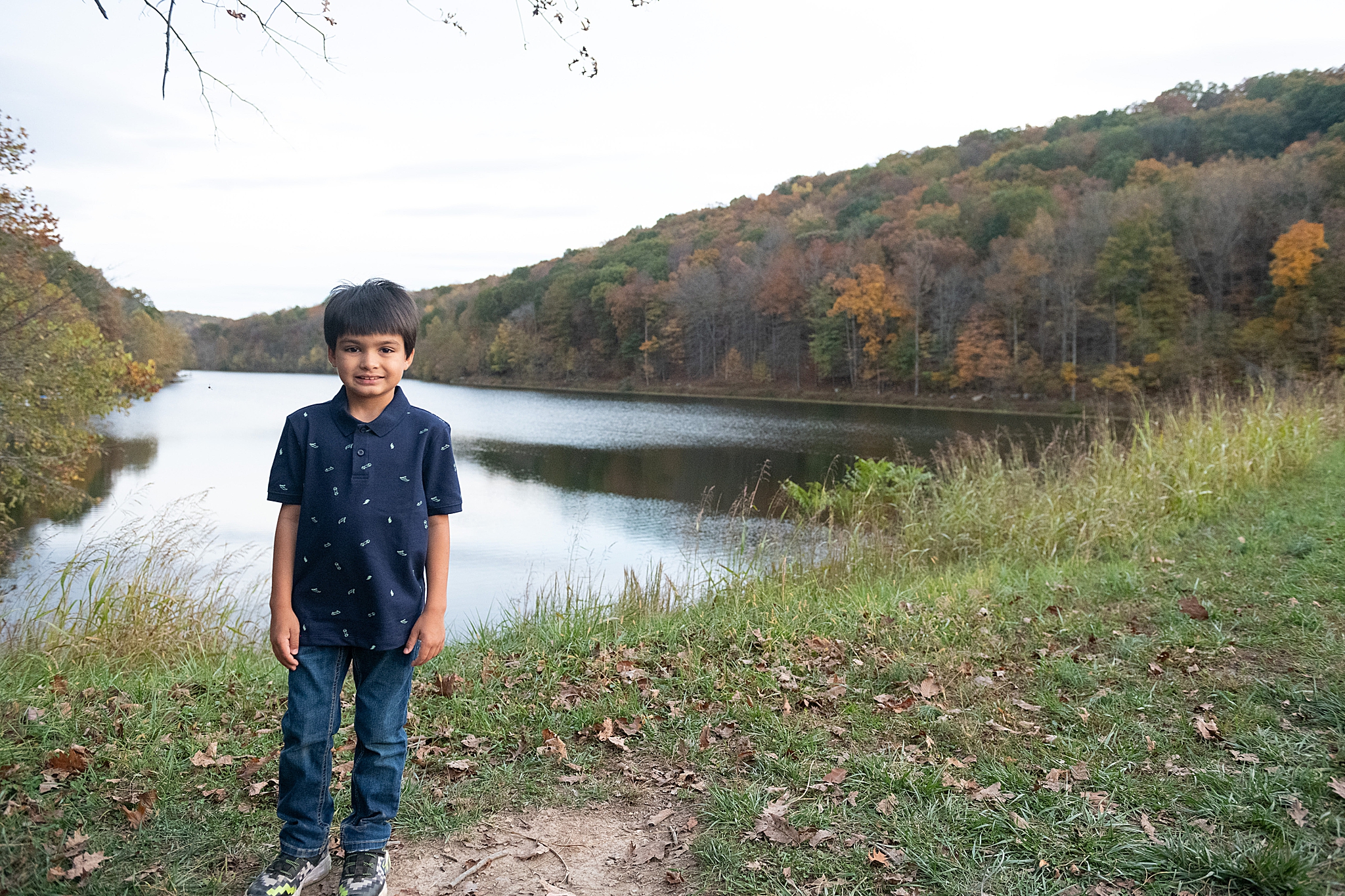 boy poses by lake in blue polo during Lake Linganore family photo session