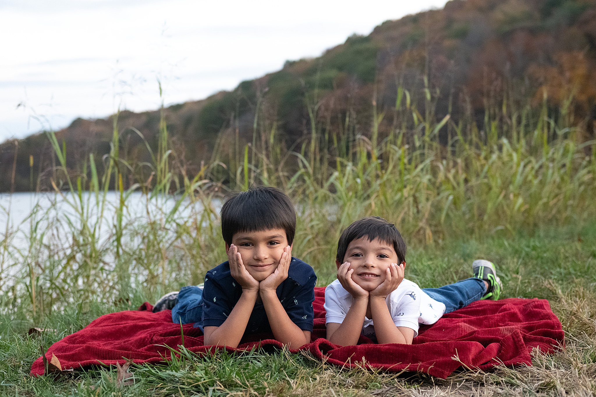 brothers lay on red blanket in front of lake in Frederick MD