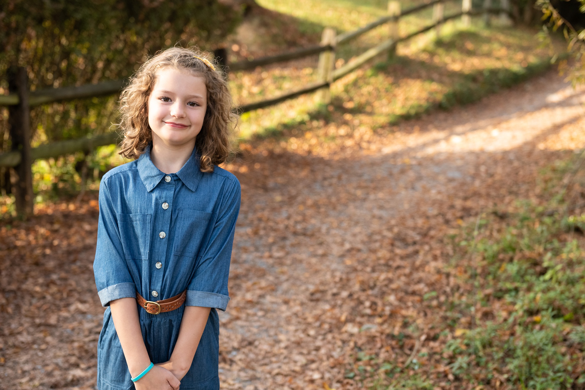 young girl in jean jumper smiles during fall family photo session 