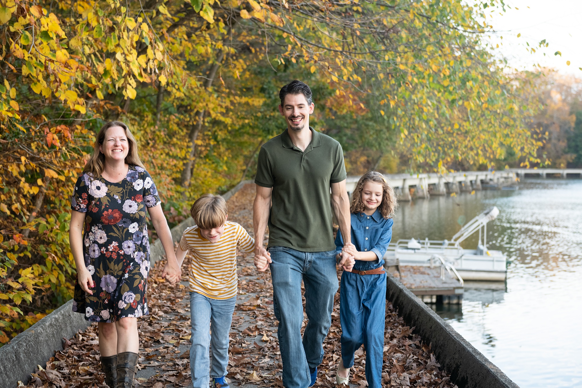 family of four walks along lake during fall family photo session