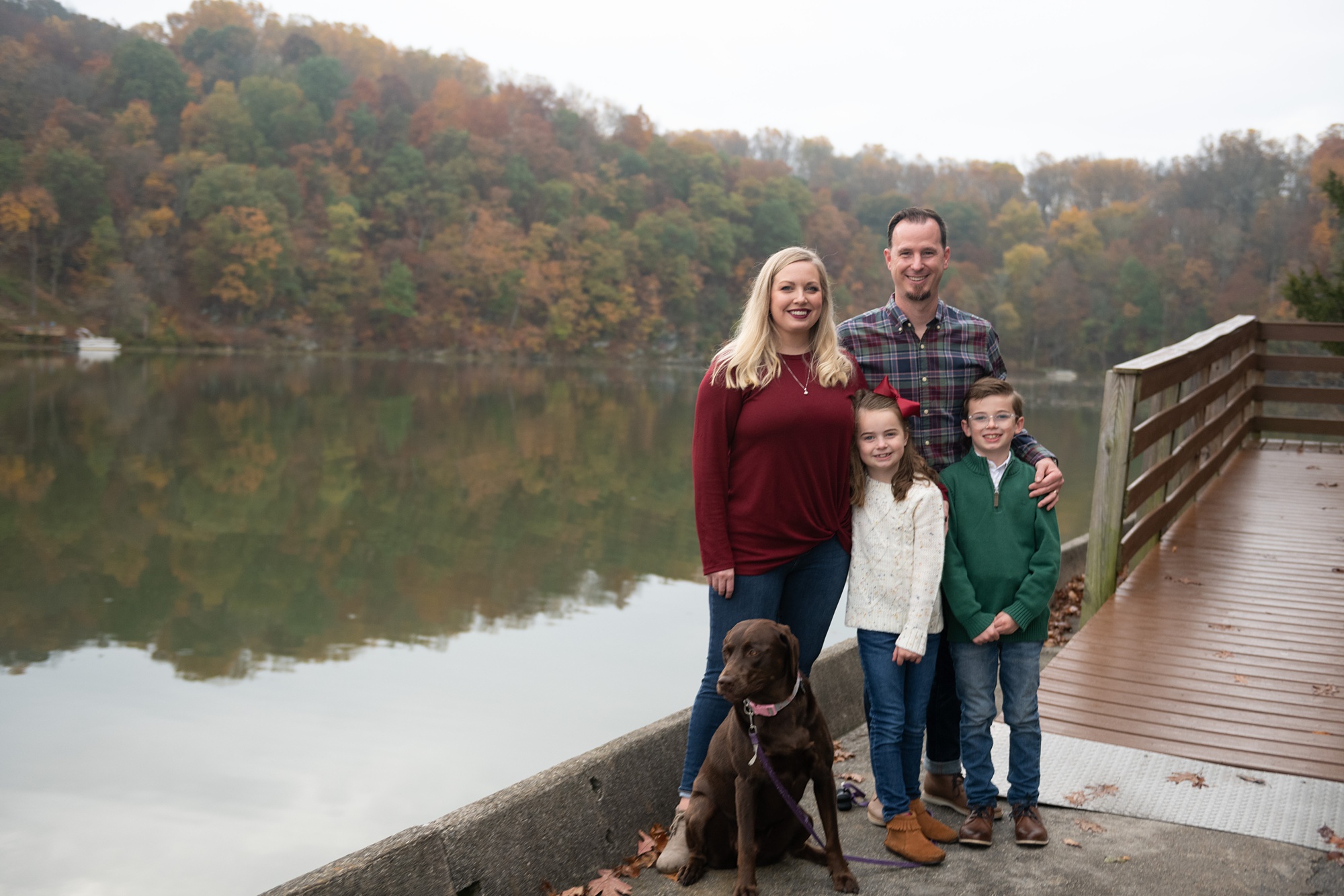 family of four poses by Lake Linganore during Family Photo Session in Frederick County
