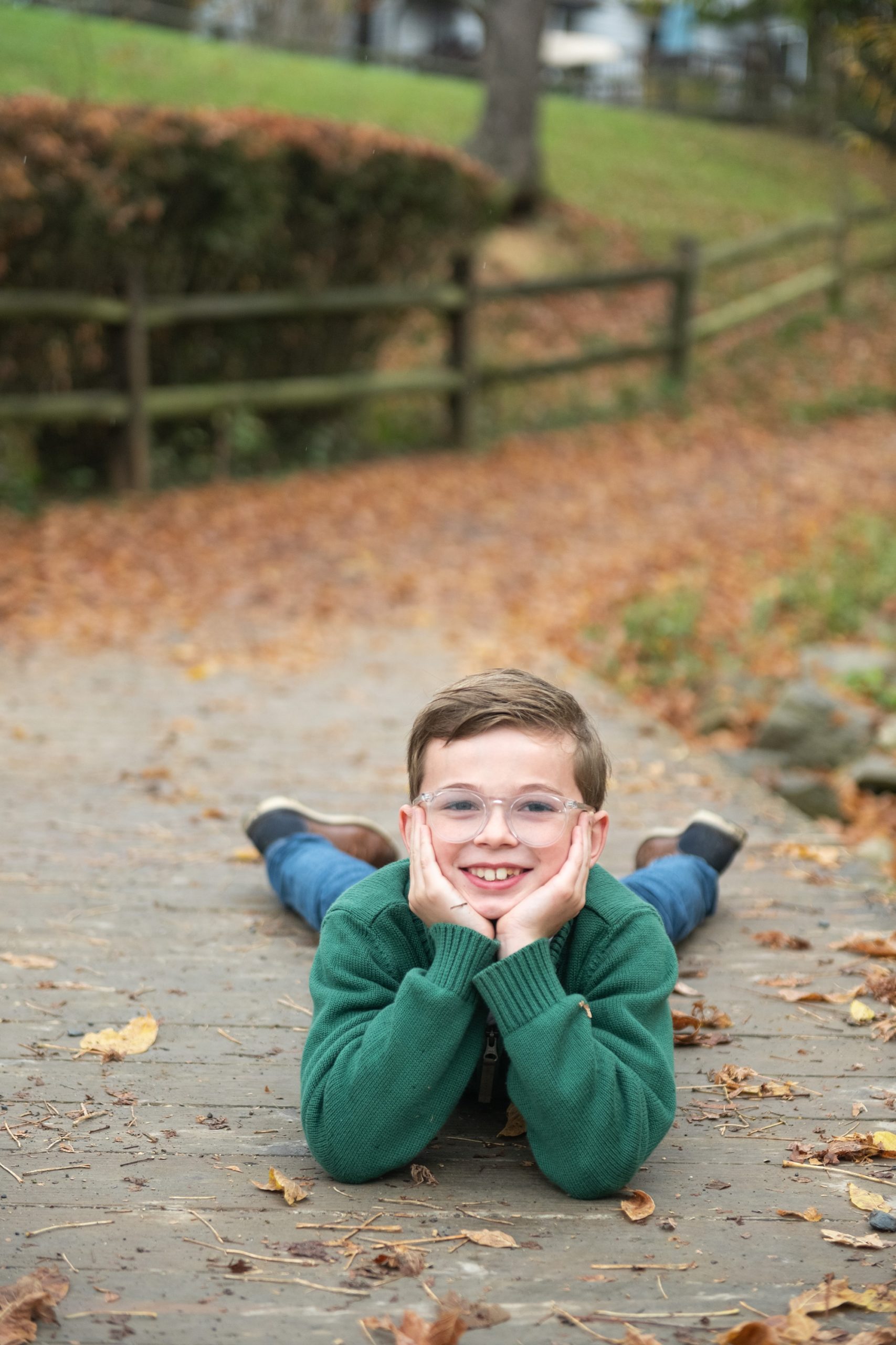 boy lays on walkway during fall family photos in Lake Linganore