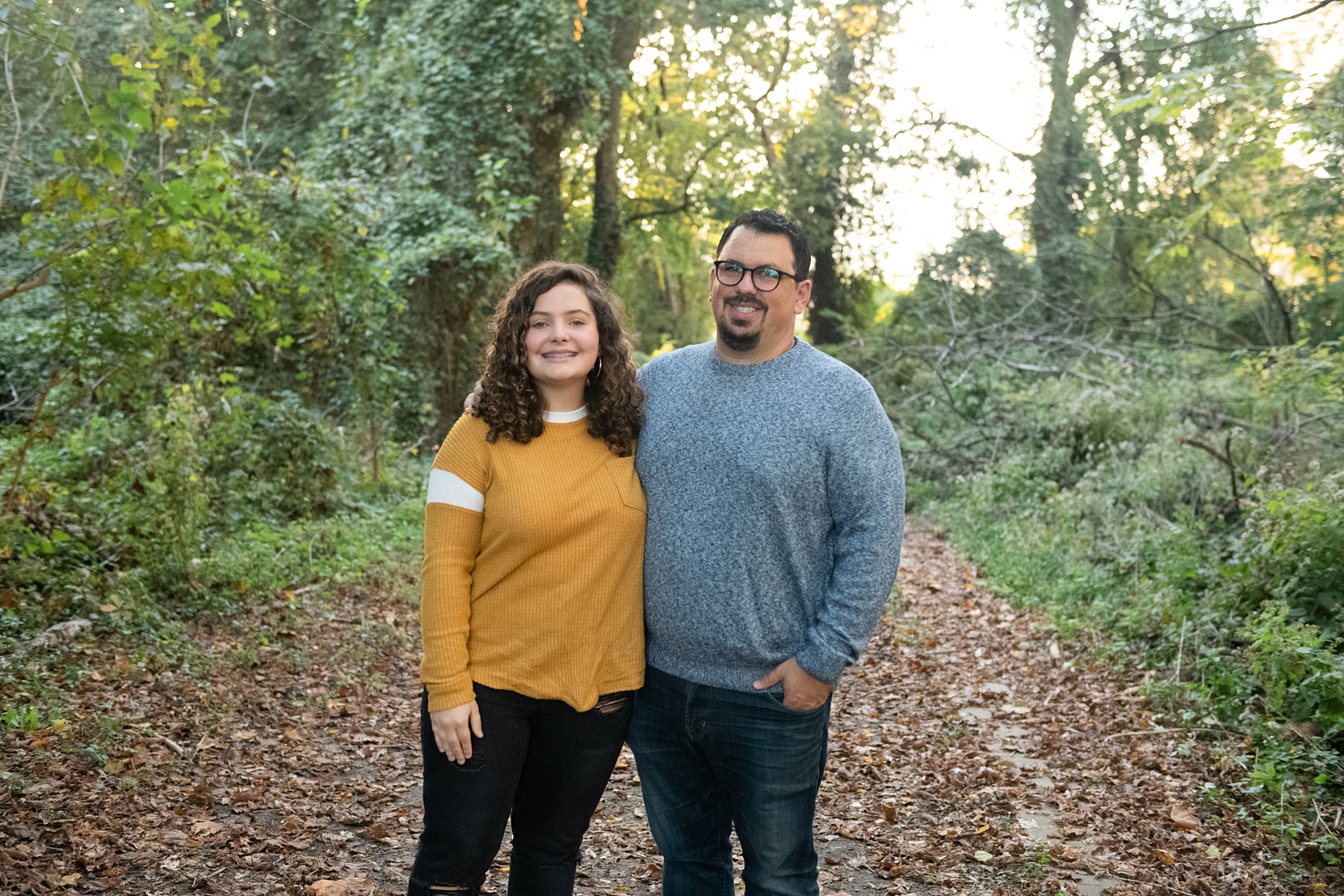 daughter and dad pose on leaf covered walkway
